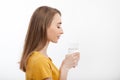 Portrait of smiling young woman standing in profile and holding a glass of water. white background. mock up. Royalty Free Stock Photo