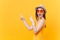 Portrait of smiling young woman in straw summer hat, orange glasses pointing index fingers aside copy space isolated on Royalty Free Stock Photo