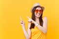 Portrait of smiling young woman in straw summer hat, orange glasses pointing index fingers aside copy space isolated on Royalty Free Stock Photo