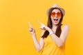 Portrait of smiling young woman in straw summer hat, orange glasses pointing index fingers aside copy space isolated on Royalty Free Stock Photo