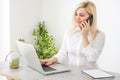 Portrait of a smiling young woman using laptop and smartphone