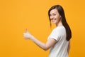 Portrait of smiling young woman in white casual clothes looking back and showing thumbs up isolated on bright yellow Royalty Free Stock Photo