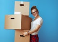 Smiling young woman holding pile of cardboard boxes on blue Royalty Free Stock Photo