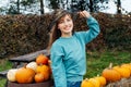 Portrait of smiling young woman in witch hat posing on pumpkins background. Female selecting best pumpkins for