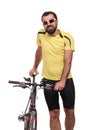 Portrait of smilling bicyclist with sunglasses and yellow shirt, posing with a bicycle, isolated on white