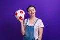 Portrait of smilling girl holding a soccer ball over isolated blue wall at studio