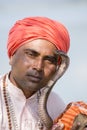 Portrait snake charmer adult man in turban and cobra sitting near the lake. Pokhara, Nepal