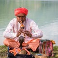 Portrait snake charmer adult man in turban and cobra sitting near the lake. Pokhara, Nepal