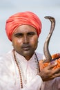 Portrait snake charmer adult man in turban and cobra sitting near the lake. Pokhara, Nepal