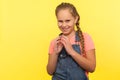 Portrait of sneaky scheming little girl in denim overalls thinking over cunning prank and smirking