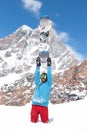 Snowboarder in blue and red, raised hands arms up hold snowboard on top of hill, snow mountains snowboarding on slopes.