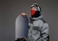 Portrait of a snowboarder wearing full protective equipment for extreme snowboarding posing with snowboard at a studio