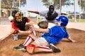 Portrait of Softball player sliding into home plate while umpire rules safe