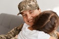 Portrait of soldier woman looking at camera with happy charming smile hugging her dark haired daughter, missing so much, returning Royalty Free Stock Photo