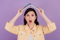 Portrait of speechless woman hold book raise hands roof figure open mouth on purple background