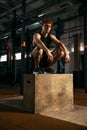 Portrait of sportive, muscular red-haired young man sitting on box, resting isolated over gym background Royalty Free Stock Photo