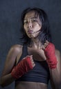 Portrait of sporty and fit fighter Asian Chinese woman using wrist wraps training mma fight sport or boxing workout looking danger