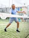 Sporty senior man playing padel on open tennis court