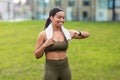 Portrait of sporty young black woman with towel checking her smartwatch or fitness tracker at city park Royalty Free Stock Photo