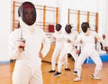 Young female in mask with foil at fencing workout