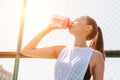 .Portrait of sporty young woman drinking cool water from bottle on summer sports field. Healthy lifestyle concept Royalty Free Stock Photo