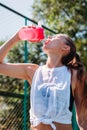 Portrait of sporty young woman drinking cool water from bottle on a summer sports field outdoors Royalty Free Stock Photo