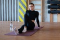 Portrait of a sporty young woman sitting in a gym on the floor on a mat Royalty Free Stock Photo