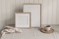 Portrait and square empty wooden frame mockups with cup of coffee. Beige linen table cloth. White beadboard wainscot