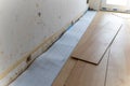 A portrait of stacked wood imitation laminate floorboards lying on some sound isolation ready to be installed to create a wooden
