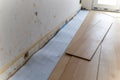 A portrait of stacked wood imitation laminate floorboards lying on some sound isolation ready to be installed to create a wooden