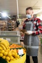 Portrait of staff using digital tablet while checking fruits in organic section of supermarket, young man grocery clerk Royalty Free Stock Photo