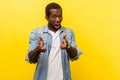 Portrait of street criminal, dangerous young man pointing with finger pistols. indoor studio shot isolated on yellow background