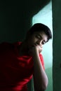 Portrait of a stressed Asian boy in front of window. An Indian melancholy boy is thinking. Sadness expression of a boy