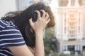 Portrait of a stressed Asian woman holding head in hands with city building background. Royalty Free Stock Photo