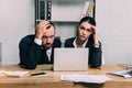 portrait of stressed business people at workplace with documents and laptop