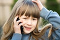 Portrait of stressed child girl with long hair talking on cell phone. Little female kid communicating using smartphone. Children