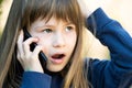 Portrait of stressed child girl with long hair talking on cell phone. Little female kid communicating using smartphone. Children