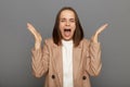 Portrait of stressed female wearing beige jacket standing and screaming, people expression and emotion, raised her arms, posing Royalty Free Stock Photo