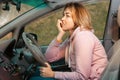 Portrait of stressed nervous woman is sitting behind the wheel of a car and bites her nails. The broken windshield of Royalty Free Stock Photo