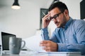 Portrait of stressed out and worried troublesome overworked businessman entrepreneur looking documents report in modern bright Royalty Free Stock Photo