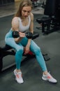 Portrait of strong caucasian disabled woman wearing prosthesis in tracksuit training and lifting dumbbell in gym