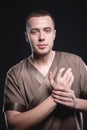 Portrait of a strong and large male masseur in special clothes with a finger at the temple reads your chin and knows all