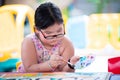 Portrait of student girl is doing art work. Asian children hold paint trays and paint brushes, drawing on paper. Royalty Free Stock Photo