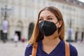 Portrait of student girl wearing a protective KN95 FFP2 black mask walking in city street