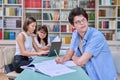 Portrait of student guy at desk inside college library, female student together with teacher preparing for exam. Royalty Free Stock Photo