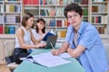 Portrait of student guy at desk inside college library, female student together with teacher preparing for exam. Royalty Free Stock Photo