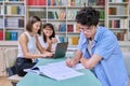 Portrait of student guy at desk inside college library, female student together with teacher preparing for exam. Royalty Free Stock Photo