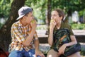 Portrait of students in a city park, teenage schoolchildren a boy and a girl sitting on a bench, resting and eating apples Royalty Free Stock Photo