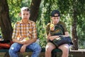 Portrait of students in a city park, teenage schoolchildren a boy and a girl sitting on a bench, resting and eating apples Royalty Free Stock Photo