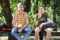 Portrait of students in a city park, teenage schoolchildren a boy and a girl sitting on a bench, resting and eating apples Royalty Free Stock Photo